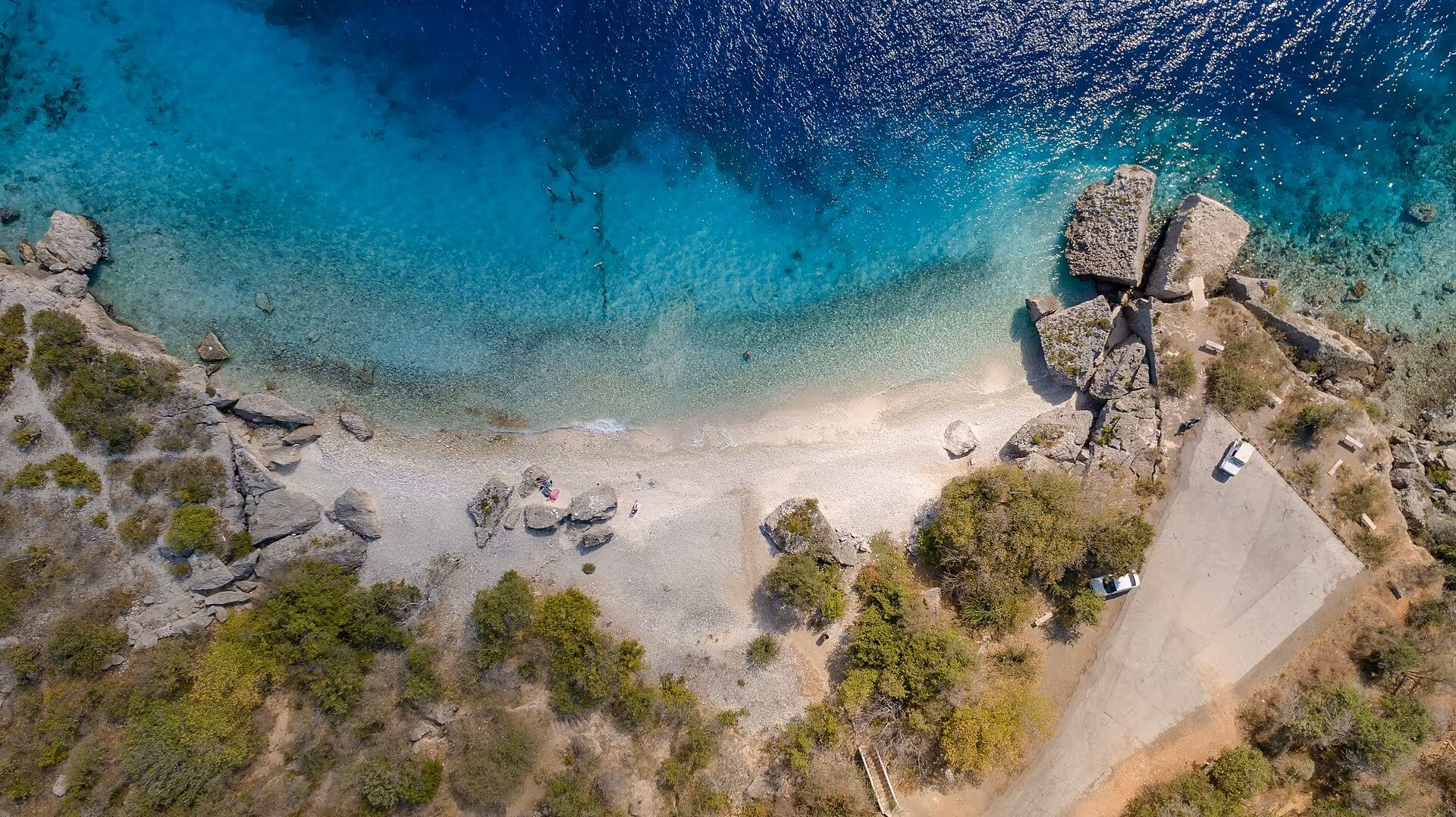 Top-down aerial of Director's Bay: the small beach, boulders and access road