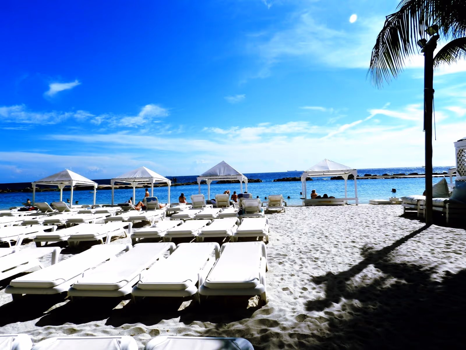 Mambo Beach: loungers and daybeds behind the breakwater lagoon