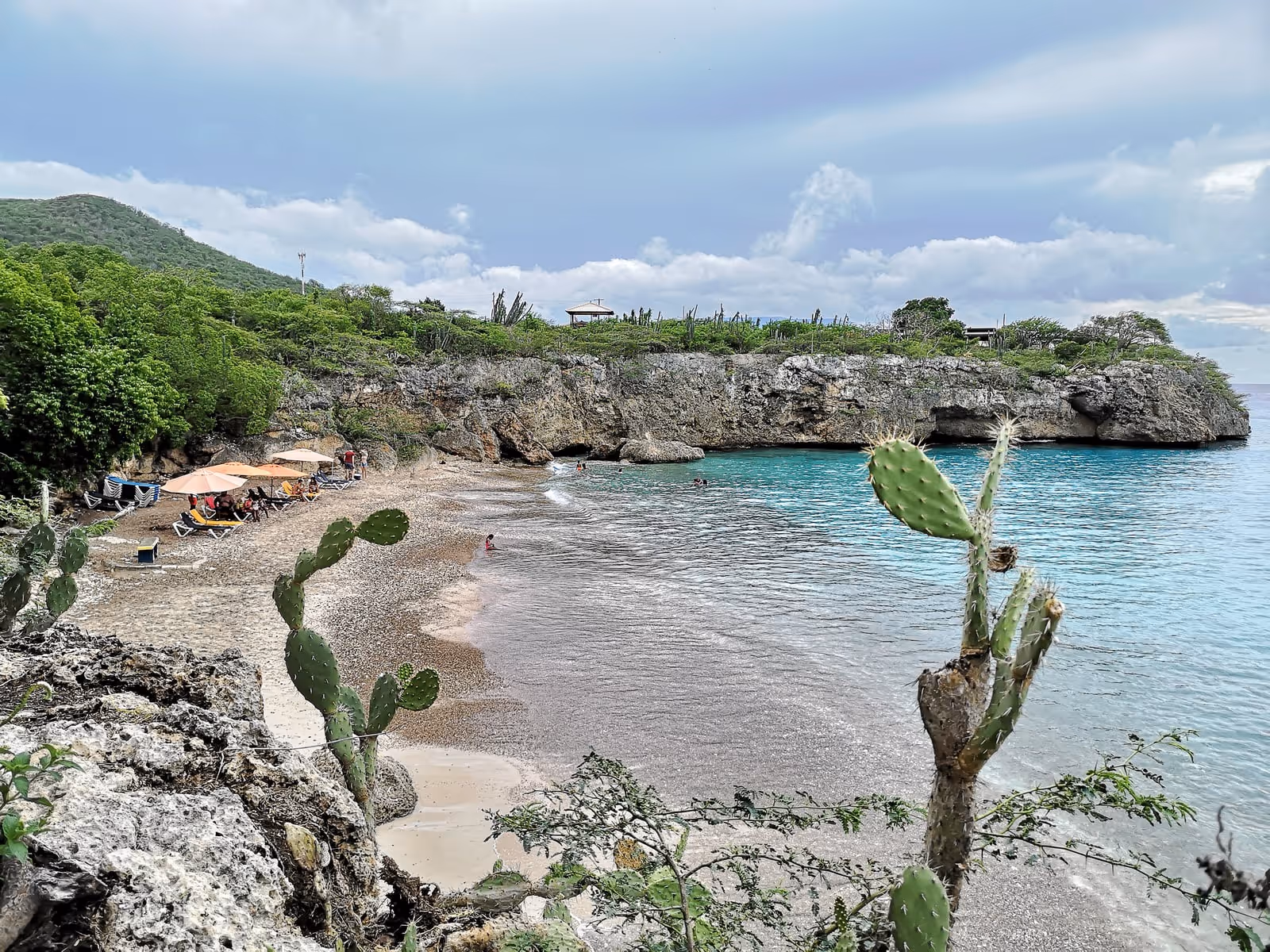 Playa Jeremi from the north: the cove closed off by its limestone cliff, vendor umbrellas on the sand